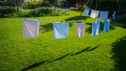 Freshly washed pillowcases drying on a clothesline in a sunlit backyard. © StockMediaSeller