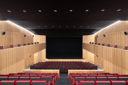 Modern auditorium interior with red seats and wooden panels