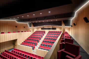 Modern auditorium with red seats and wooden panels