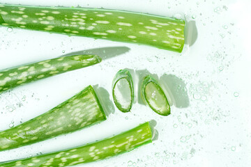 Fresh aloe vera slices on a wet surface for cosmetic use