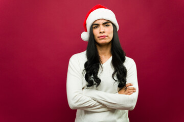 Frowning young woman with long black hair wearing a santa hat during the christmas season