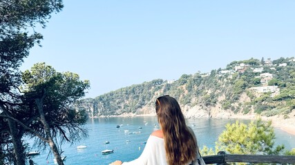 Woman tourist with her back to the cove on the Costa Brava.