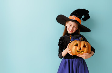 girl in witch costume with Halloween pumpkin