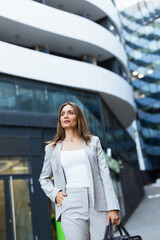 Obraz premium Professional young woman confidently strides through a modern urban landscape, showcasing her style and determination in city attire
