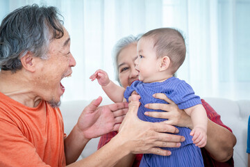 A man and a woman are sitting on a couch with a baby in between them. The baby is wearing a purple outfit. Scene is warm and loving, as the family is spending quality time together