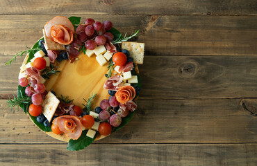 Christmas wreath made with charcuterie products, tomatoes, olives and cheese. View from above.