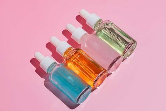 Colorful Cosmetic Serum Bottles on Pink Background