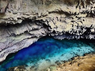 Mystery cave with grey silver stone ceiling and blue crystal clear water. Banggai Island, Sulawesi, Indonesia, Asia.