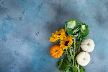 Bouquet of fall flowers and pumpkins on gray background, top view