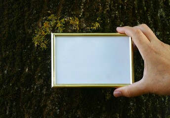 Mock up - man hold in hands golden frame nature background