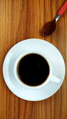 Cup of coffee and  special medium roast ground coffe in spoon on the wooden table.
