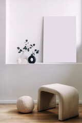 Minimalist interior design featuring a light-colored stool and decor items on a shelf in a modern living space with natural wood flooring and soft lighting