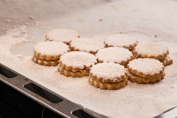 Christmas baking: German jam cookies (Spitzbuben) with sugar icing on baking paper