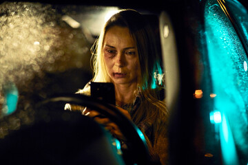 Bruised up concerned woman on a phone call while driving at night