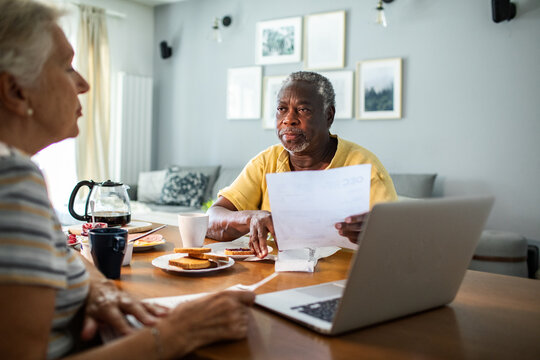 Diverse senior couple reading bills on the couch at home
