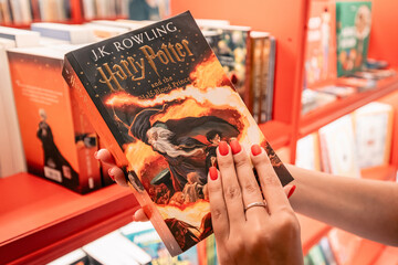 Fototapeta premium 09 July 2024, Istanbul, Turkey: A fan holding the Harry Potter book Half-Blood Prince in a bookstore, browsing the pages