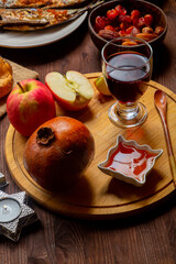 Challah, honey, apple and pomegranate and wine on the table, menorah and candles for the holiday on...