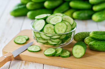 chopped cucumbers slices in a clear glass bowl on a wooden table, selective focus.