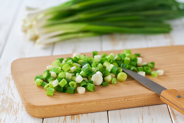 cutting board with spring onions on table, selective focus.