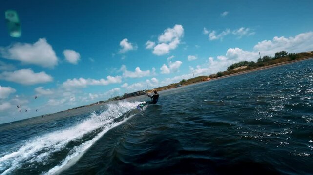 Slow motion tracking pan follows kiteboard surfer turning tight spraying water