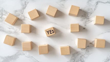 Scattered wooden cubes display the word YES in bold black ink, showcasing varying shades and textures, emphasizing choice and clarity in a simple backdrop