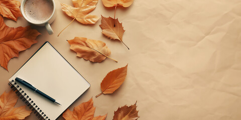 Minimalist flat lay with notepad, pen, coffee cup and autumnal leaves on soft beige paper texture background. Great design with copy space.