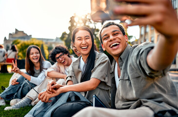 Group of happy smilling modern students taking a selfie outdoors on campus.