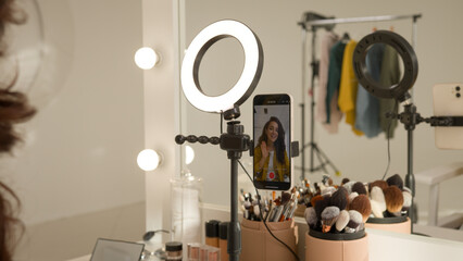 Glad Caucasian woman blogger girl influencer filming video mobile phone on stabilizer lamp studio female vlogger streamer talk demonstrating shadow palette do makeup tutorial beauty stream blog mirror