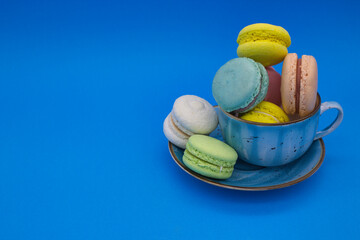 Colorful Macarons in a Blue Cup on a Vibrant Background