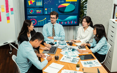 Diverse group of business analyst team analyzing financial data report. Finance data analysis chart and graph dashboard show on TV screen in meeting room for strategic marketing planning. Habiliment