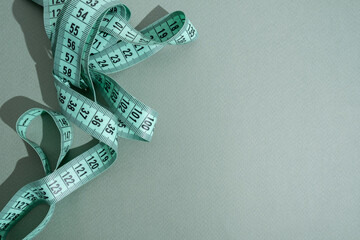 Green measuring tape on a colored background. Tool for measuring length and volume. Tape for...