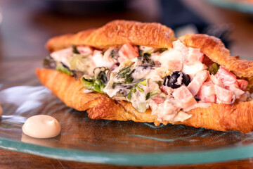 Croissant with tuna, lettuce, tomatoes, olives and mayo, brunch food close up