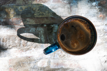 coffee in a mug close-up with foam on a gray background, morning light rays, contrast, top view, place for writing, selective focus, morning coffee