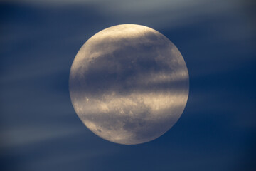 photograph of the full moon partially covered with clouds