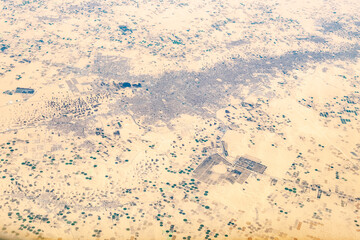 Aerial view of arid Sahara desert dried lands sandy reg with dried out plants. Center-pivot irrigation, central pivot irrigation, water-wheel, and circle irrigation systems and agricultural stations.