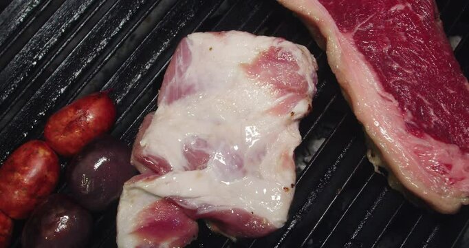 Beautiful slow motion shot of a chef placing a piece of beef steak on a grill for grilling inside a restaurant kitchen.