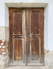Old wooden damaged brown door of brick building