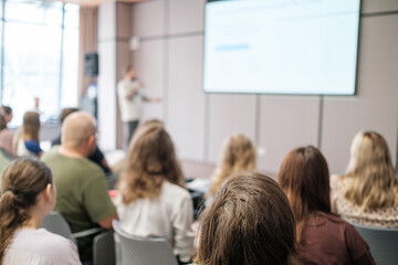 Group of people attentively listening to a speaker in a professional seminar setting, showcasing...
