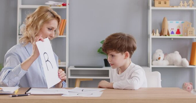 Speech therapist or teacher is working with a child, practicing an exercise to improve communication skills. Professional doctor logopedist in helping children develop language abilities.