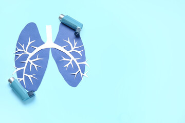 Paper lungs and asthma inhalers on blue background
