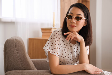Beautiful Asian woman in stylish sunglasses at home