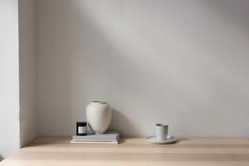 Elegant Scandinavain interior. Wooden table with a stack of magazines, books. White vase, candle. Cup of coffee, tea. Empty white wall background mockup. Beautiful living room still life, home decor.