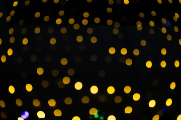 Luzes natalinas douradas, fora do foco, em bokeh, com fundo preto.