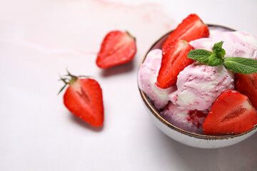 Bowl of strawberry ice cream with berries and mint on pink table