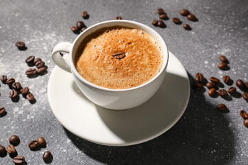 Cup of delicious espresso and coffee beans on grey background, closeup