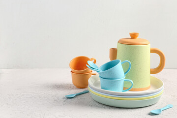 Plates with cups, teapot and spoons for baby on white table