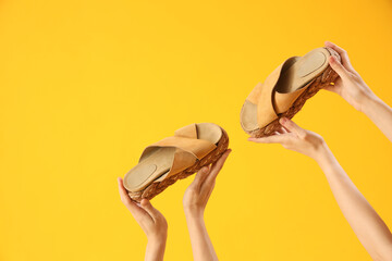 Hands with flip-flops on yellow background