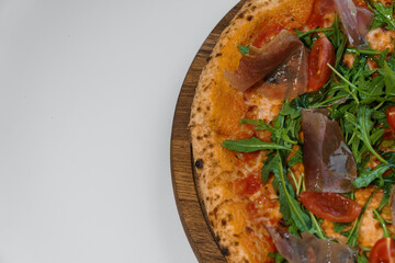 Pepperoni pizza with arugula and prosciutto. Meat pizza with cheese, cherry tomatoes and fresh arugula on a white background
