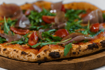 Pepperoni pizza with arugula and prosciutto. Meat pizza with cheese, cherry tomatoes and fresh arugula on a white background