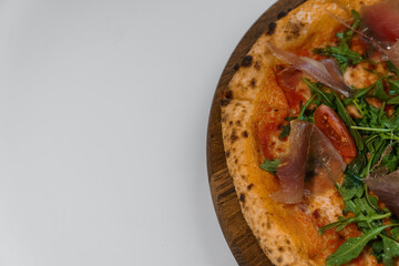 Pepperoni pizza with arugula and prosciutto. Meat pizza with cheese, cherry tomatoes and fresh arugula on a white background